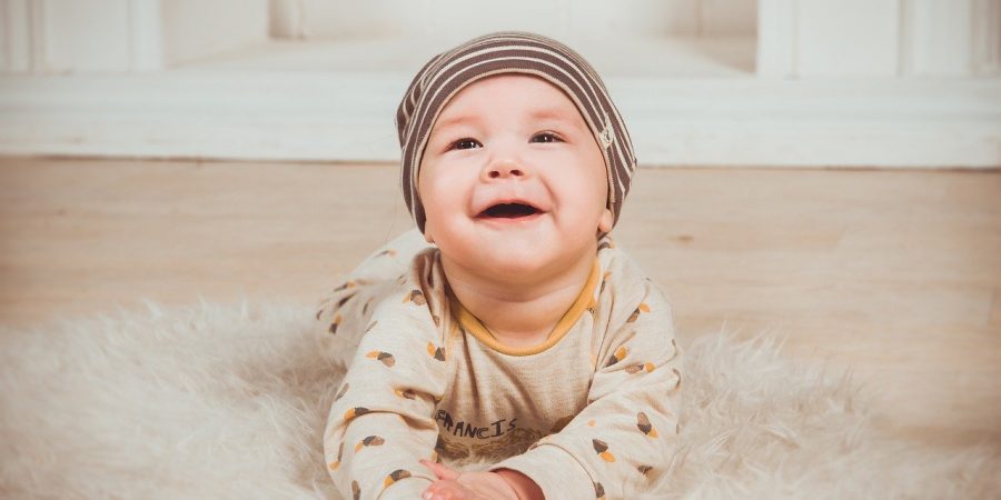 bébé qui sourit en étant allongé sur le sol