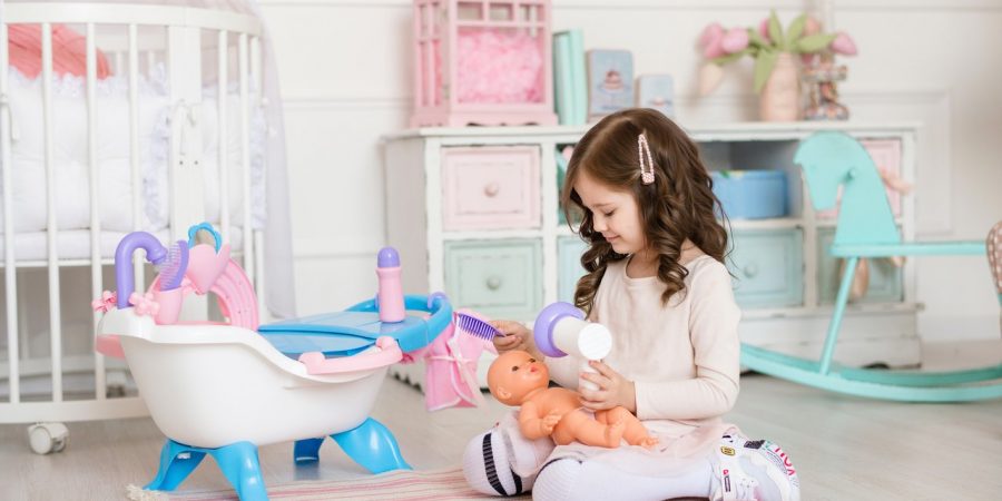 petite fille qui sèche et coiffe les cheveux de son poupon